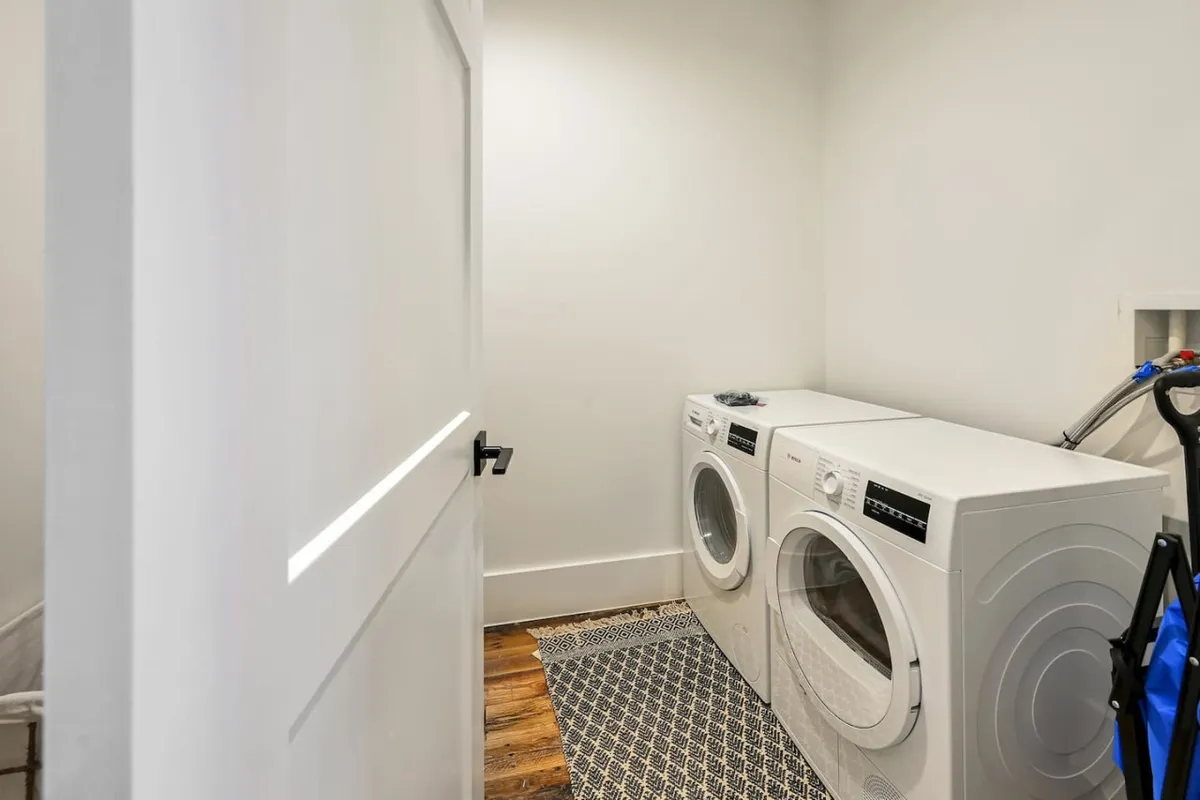 A bright laundry space with a modern washing machine and dryer, accented by a tidy rug. The area is organized and efficient, capturing the convenience and practicality at the heart of eco-friendly living.